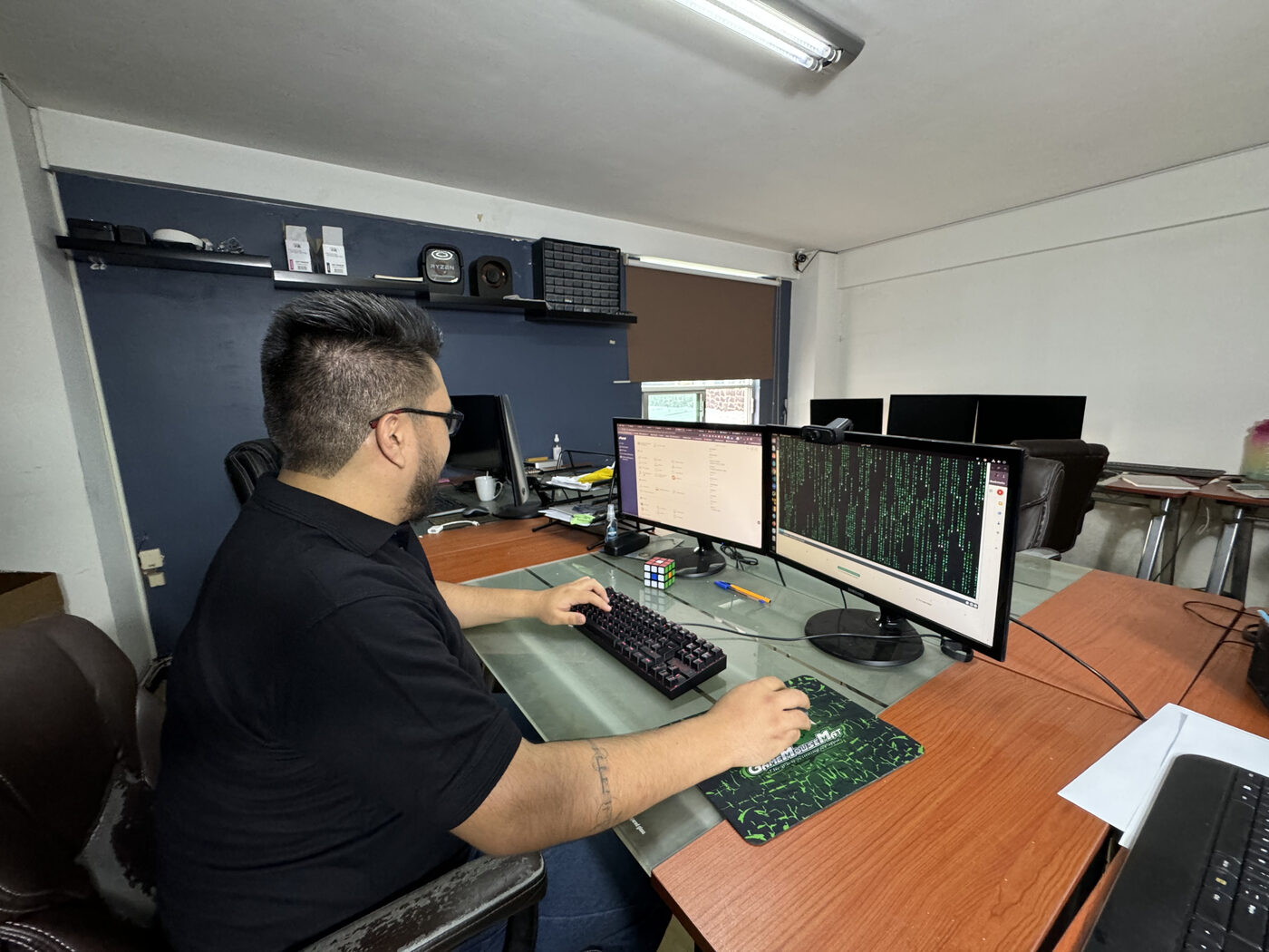 Isma Haro trabajando frente a tres monitores con código en pantalla.