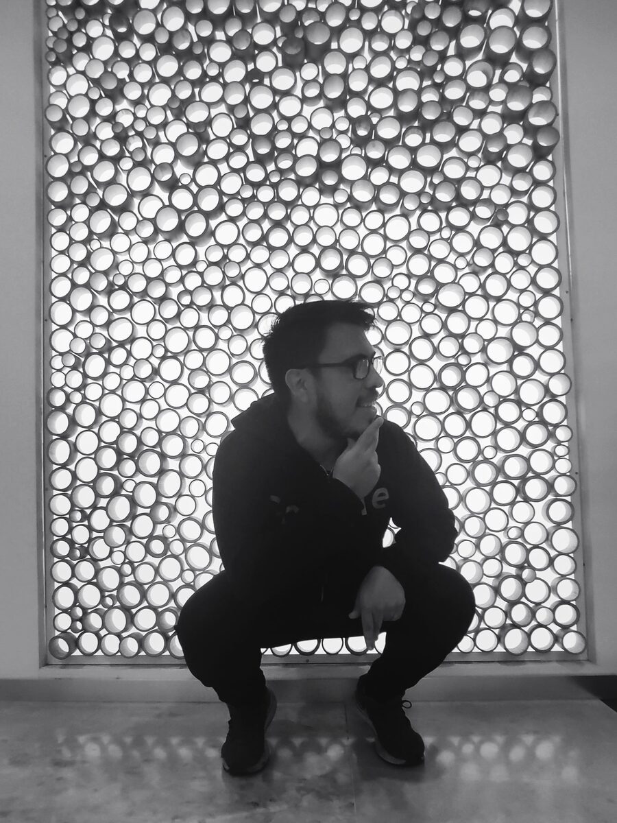 Isma Haro, en cuclillas frente a una pared de círculos.